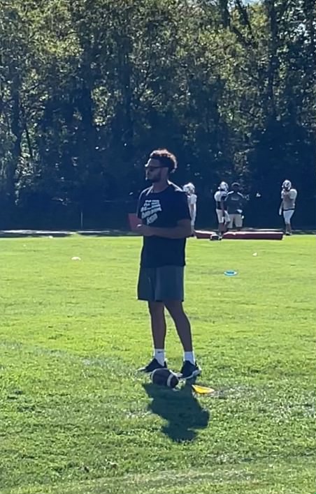 Coach Israel Taylor looks on as his players run a wide receiver drill. This is his first year of coaching after graduating from St. Ambrose.